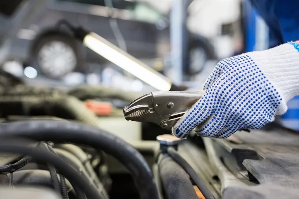 KFZ-Mechaniker schraubt am Auto